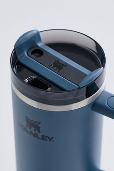 a blue travel mug with an open lid and a handle on the side that is holding a cell phone