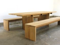 two wooden benches sitting next to each other in a room with white walls and concrete flooring