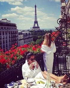 two people sitting at an outdoor table with food in front of the eiffel tower