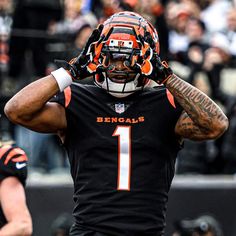 a close up of a football player holding his hands behind his head with fans in the background