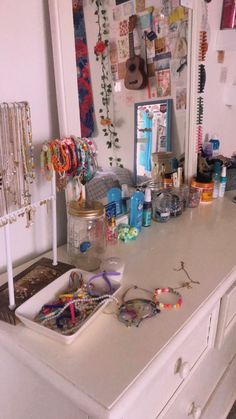 a white dresser topped with lots of jewelry