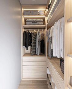 a walk - in closet with white drawers and wooden shelves, clothes hanging on hangers