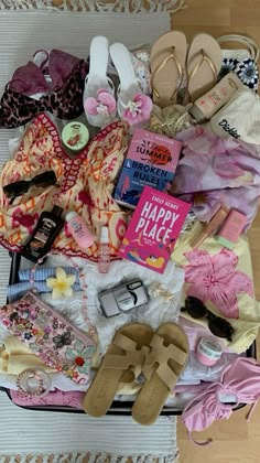 an open suitcase filled with clothing and shoes on top of a floor next to a rug