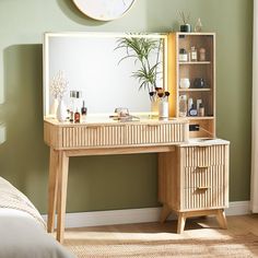 a wooden desk topped with a mirror next to a dresser under a wall mounted clock