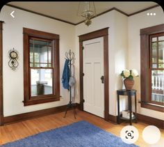 a room with two windows, a blue rug and a coat rack on the wall