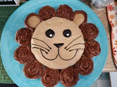 a lion cake on a blue plate with chocolate frosting and icing roses around it