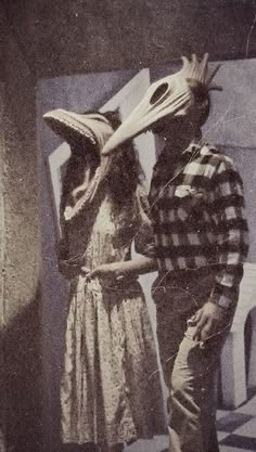 two people standing next to each other in front of a building with newspaper coverings on their heads