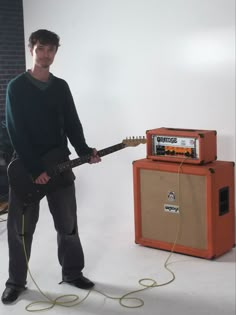 a man standing next to an amp and guitar