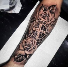 a man's arm with roses and cross on the inside of it, in black and white