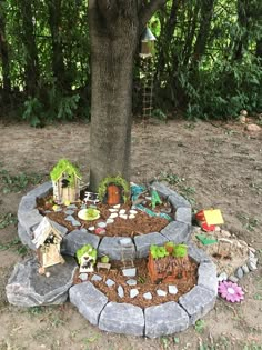 a small garden in the shape of a circle with rocks and plants around it, under a tree