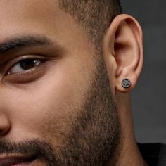 a close up of a person wearing an earring and looking at the camera with a smile on his face