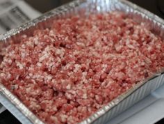 a metal pan filled with ground meat on top of a stove