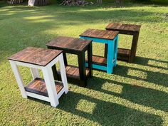 three wooden tables sitting on top of a grass covered field next to eachother