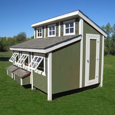 a green and white shed sitting on top of a lush green field