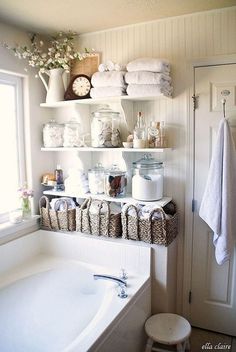 a bath room with a tub and shelves filled with towels