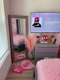 a bedroom with pink bedding, mirror and television in it's centerpiece