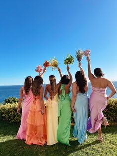 the bridesmaids are holding their bouquets in front of the ocean and blue sky