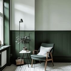 a chair and table in a room with green paneled walls, white flooring and wooden floors