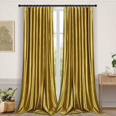 a living room with a window covered in gold colored drapes and a rug on the floor