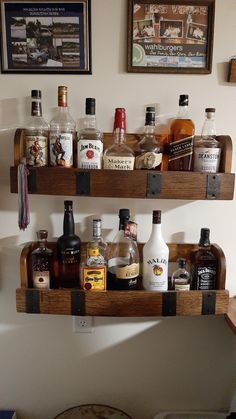 two wooden shelves filled with liquor bottles on top of a counter next to a wall