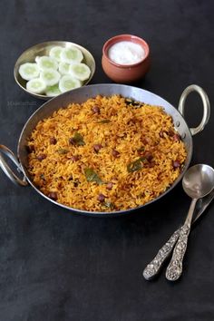 a pan filled with rice next to two spoons