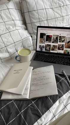 a laptop computer sitting on top of a bed next to an open book and cup of coffee