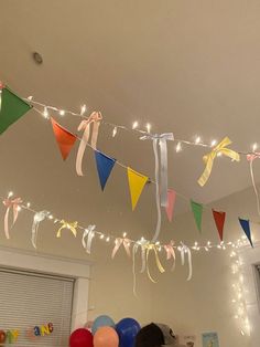 some balloons and streamers are hanging from the ceiling in a room with white walls