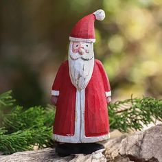 a red and white santa figurine sitting on top of a rock