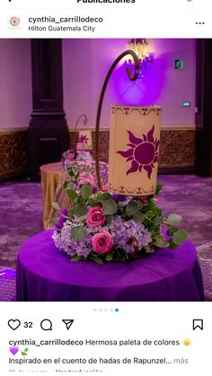 a purple table topped with a basket filled with flowers and greenery on top of it