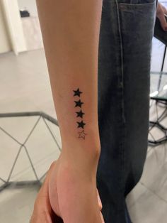 a person's arm with three stars on the left side of their wrist tattoo