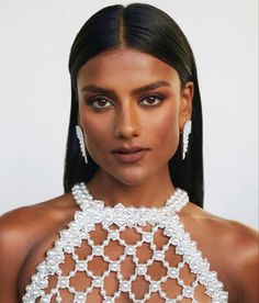 a woman with long black hair wearing white jewelry