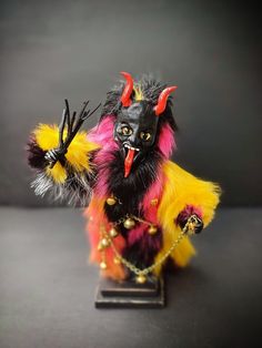 a small figurine is dressed in black and yellow with red, orange, and yellow feathers