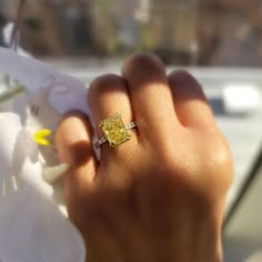 a woman's hand holding a yellow diamond ring