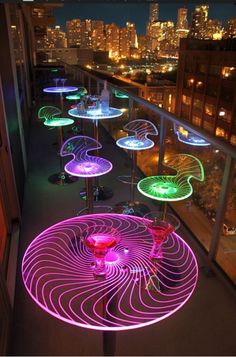 colorful lights on the outside of an apartment building at night, with city lights in the background