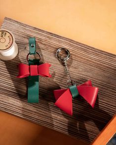 two red and green bow key chains sitting on top of a wooden table next to a bottle