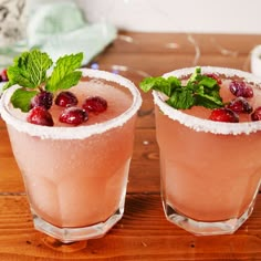 a pink drink with mint and cranberry garnish in a glass on a wooden table