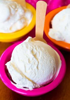 two bowls filled with ice cream on top of a wooden table next to orange and yellow plates