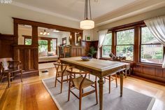 a dining room table and chairs in front of two large windows with wood trimmings