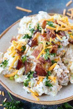 a white plate topped with potato salad covered in bacon, cheese and parmesan