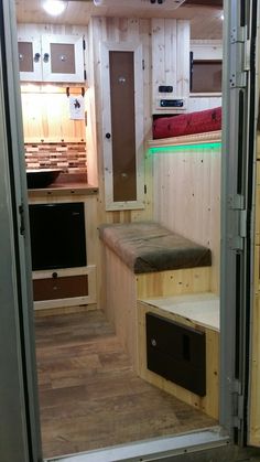 the inside of a tiny home with wooden walls and flooring, built in to an outside kitchen area