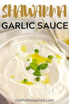 a bowl filled with white sauce and garnished with green leaves on the side