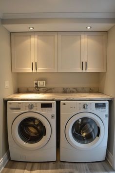 a washer and dryer in a small room with white cabinets on the wall