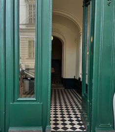 an open green door with black and white checkered floor