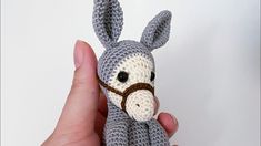 a crocheted donkey stuffed animal is being held by a person's hand