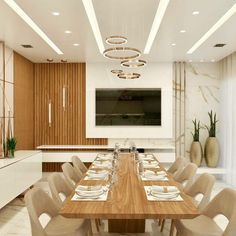 a dining room table set with white plates and place settings in front of a flat screen tv