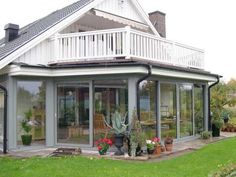 a house with many potted plants in front of it and a deck on the outside