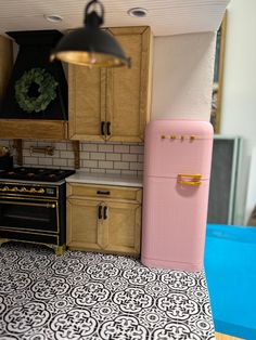 a pink refrigerator freezer sitting inside of a kitchen next to a stove top oven