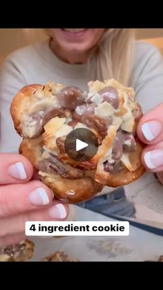 a woman is holding up a chocolate covered doughnut