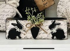 an old suitcase is decorated with black and white bunny silhouettes on it, tied to a burlock