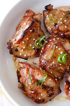 some chicken with sesame seeds and green onions on a white plate